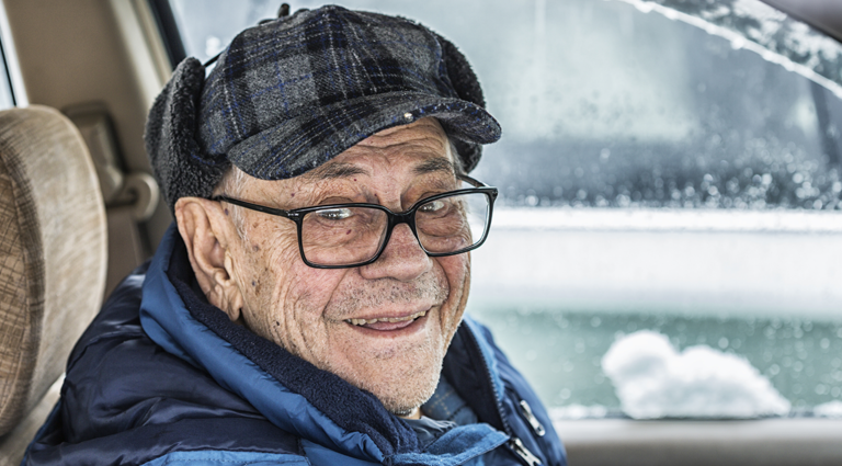 older man sitting inside car during winter